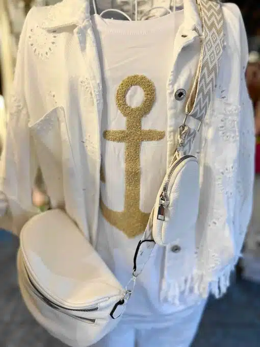 Weiße Bluse mit goldenem Ankermuster und eine weiße Alma Tasche Umhängetasche.