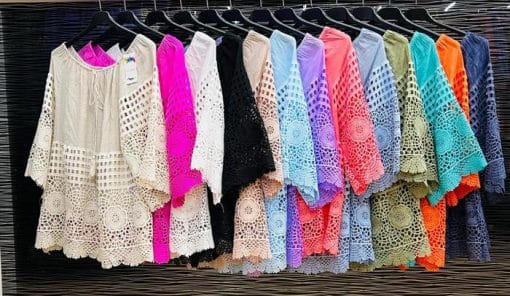 Willkommen in einer Reihe farbenfroher Welcome Tunika-Hemden, die an einem Kleiderständer hängen.