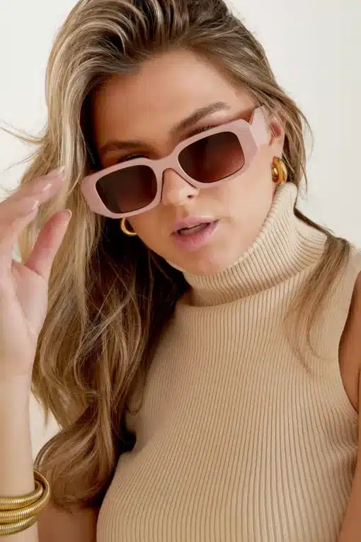 Das Model trägt eine rosafarbene Trend-Sonnenbrille.