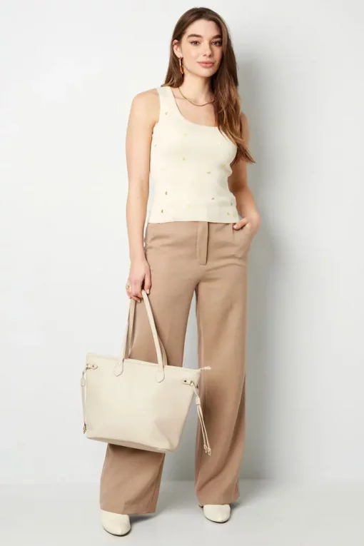 Eine Frau in einem Mein Herz-Top und einer weiten Hose mit einer Einkaufstasche.
