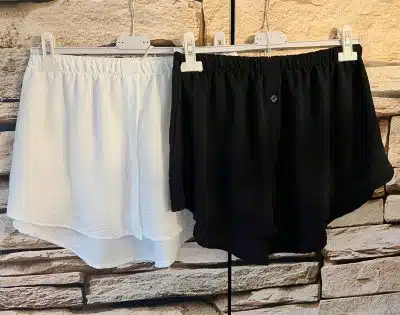 Zwei schwarz-weiße Shorts, Blusentäuscher, hängen an einer Wand.