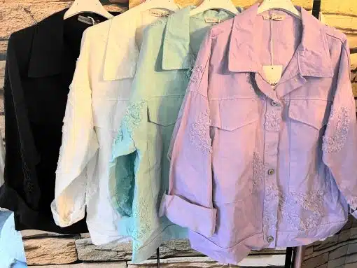 Vier verschiedenfarbige Hemden hängen an einem Gestell. Der Produktname „Heard Jeansjacke“ wird in der geänderten Beschreibung nicht erwähnt.