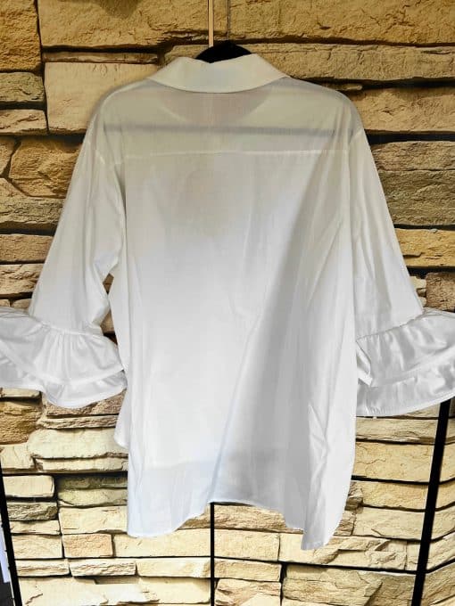 Eine schicke Bluse mit Rüschenärmeln, die an einem Kleiderbügel hängt.