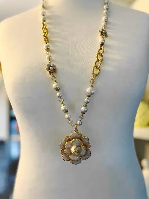 Eine Schaufensterpuppe, die eine Blumenperlenkette trägt, die mit einer Blume und Perlen verziert ist.
