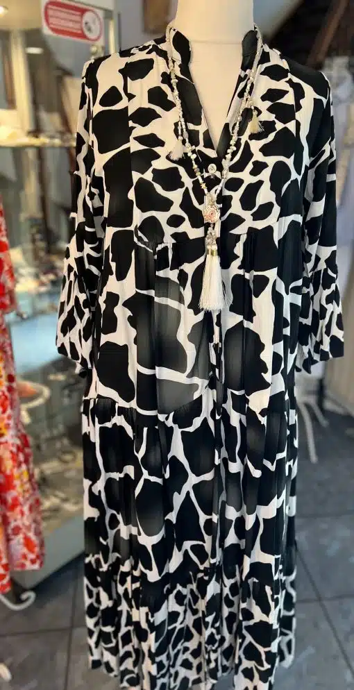 Schaufensterpuppe mit schwarz-weißem Maxikleid mit Kuhmuster und Quastenhalskette.
Produktname: Kleid