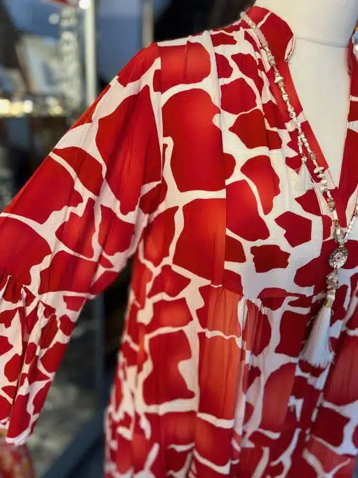 Rot-weiß gemustertes Maxi-Herbstkleid mit Quastendetail, ausgestellt in einem Geschäft.
