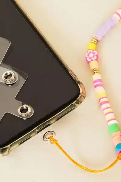 Smartphone mit einem farbenfrohen Lanyard-Pad aus Perlen und einer Kameraobjektivbefestigung.