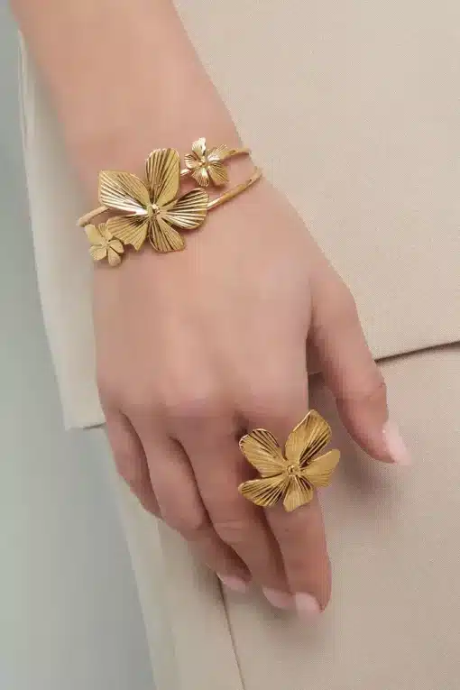Die Hand einer Frau ist mit goldenem Blumenschmuck geschmückt, mit einer Bohaim-Armspange und einem Ring.