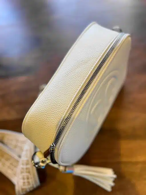 Eine weiße Umhängetasche von DC Tasche auf einem Holztisch.