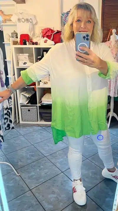 Eine Frau macht im Spiegel ein Selfie und trägt eine Colourblock-Bluse.
