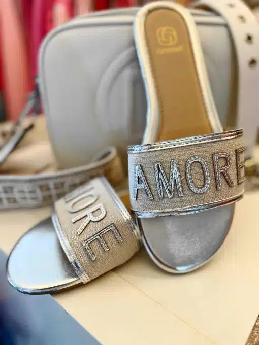 Ein Paar **Amore Schlappen**-Schuhe mit dem Wort „amore“ auf den Riemen.