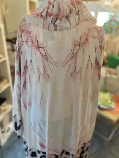 Ein transparenter Angels-Kaftan mit federähnlichem Aufdruck, der an Engel erinnert und über einer Schaufensterpuppe drapiert ist.
