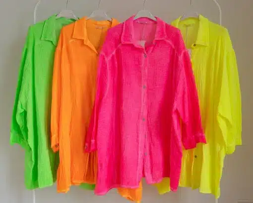 Fünf leuchtend farbige Musselin-Blusen hängen ordentlich auf einer Stange, in einem Farbverlauf von grün nach gelb angeordnet.