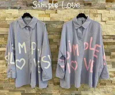 Zwei gestreifte Blusen von Semple Love mit dem aufgemalten Satz „Semple Love“ hängen nebeneinander vor einer Backsteinmauer, über ihnen steht ein Schild mit der Aufschrift „Semple Love“.