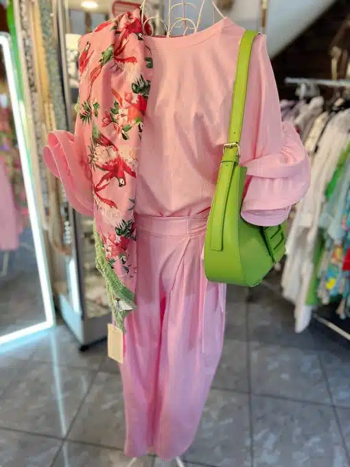 Ein rosa Kimono mit Blumenmuster und ein passendes schlichtes rosa Kleid, präsentiert auf einer Schaufensterpuppe mit einer grünen Umhängetasche von Cherry´s Shirt in einem Bekleidungsgeschäft.