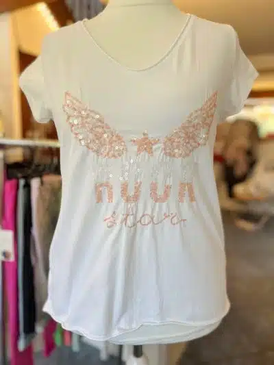 Ein in einem Geschäft ausgestelltes „Rockstar-Shirt“ mit schimmernden flügelartigen Verzierungen auf den Schultern und einem kursiven Text in der Mitte, der lautet: „Nana & Nana.“