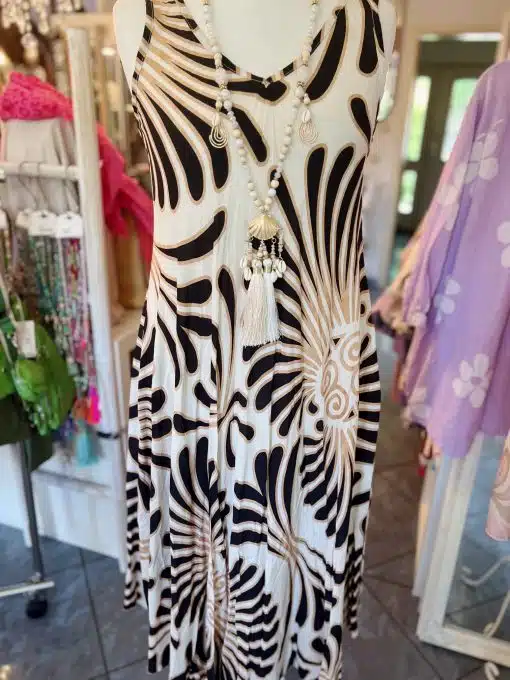Ein ärmelloses, knielanges Sommerkleid von Iland mit einem schwarz-weißen zebraähnlichen Muster, präsentiert auf einer mit weißem und silbernem Schmuck geschmückten Schaufensterpuppe in einer hell erleuchteten Boutique.