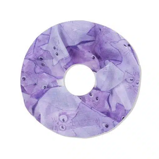 Ein runder lilafarbener **Cat Loop Schal** aus Stoff mit skurrilen Illustrationen im Design. Das Accessoire zeigt verschiedene verspielte und süße Katzengesichter auf helllila Hintergrund.