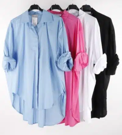 Vier klassische Langarmhemden zum Knöpfen in Blau, Rosa, Weiß und Schwarz hängen auf schwarzen Kleiderbügeln. Die Ärmel jeder Basic Classic Hemdbluse sind hochgekrempelt.