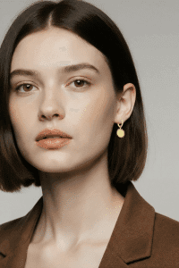 Mit deinem glatten braunen Haar und dem modernen Blazer setzt du die eleganten Solar Ohrstecker stilvoll in Szene