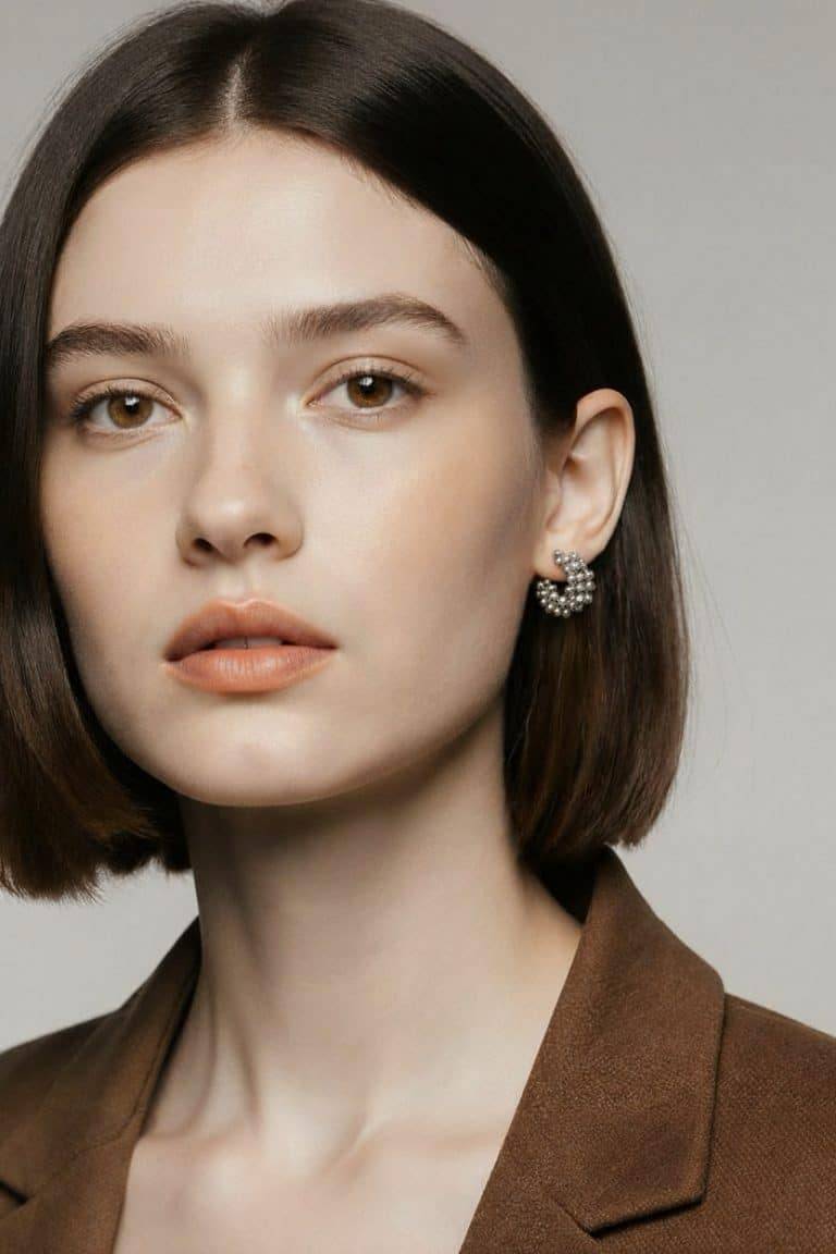 Setz ein Statement mit deinem Look: Kurzes braunes Haar, brauner Blazer und auffällige Aurora Hoops aus Silber - mutig und modern.