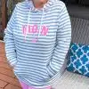 Stell dir vor: Du genießt einen entspannten Tag auf deiner Terrasse, die Sonne kitzelt dein Gesicht – und du strahlst im Zwillingsherz Damen Hoodie „MOIN“. Die hellblauen und weißen Streifen sind ein echter Hingucker, dazu die leichte Kapuze und das superweiche Material. Kombiniert mit einer coolen Hose in Pastellrosa setzt du stylische Akzente und versprühst gute Laune. Lehn dich zurück, Schnaps dir deinen Lieblingsdrink – mit diesem Look bringst du Frische und nordischen Charme in jede Auszeit!.