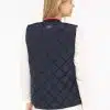 Du trägst eine dunkelblaue "Classic Diamond"-Weste, die deinen Rücken stilvoll betont und jedes Outfit auf ein neues Level hebt. Über dem weißen, langärmeligen Shirt kommt das zeitlose Design besonders modern zur Geltung - so kombinierst du mühelos sportliche Eleganz mit urbanem Trendgefühl.