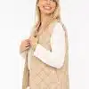 Du strahlst pure Eleganz aus - mit deiner beigen "Classic Diamond" Weste, veredelt durch goldene Knöpfe und stilvoll abgesetzte rosa Details. Über deinem weißen Langarm-Top wird dieses moderne Statement-Piece zum echten Hingucker. So setzt du modische Akzente und unterstreichst deinen individuellen Stil - zeitlos chic, selbstbewusst und einzigartig wie du.