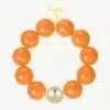 Erlebe mit dem GIUNO Bold Beads Armband mit neun orangefarbenen Perlen und goldenen Akzenten deinen stilvollen Auftritt!.