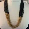 Erlebe den Wow-Effekt mit der MOANU "Lualoha" Kette! Schwarze und goldene Perlen verschmelzen in mehreren feinen Reihen zu einem modernen Eyecatcher, der deinen Stil auf ein neues Level hebt. Das Statement-Piece lässt dich strahlen - egal, ob im Alltag oder beim besonderen Anlass. Trage die "Lualoha" Kette und ziehe alle Blicke auf dich!.