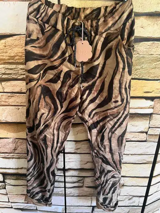 Entfessele deine Urban Wildcat: Die zauberhafte Hose im braun-schwarzen Zebra-Print ist dein Statement-Piece für jedes Abenteuer. Vor stilvoller Steinoptik präsentiert, bringst du mit diesem Blickfang Wildheit und Eleganz aufregend auf den Punkt - bereit, die Stadt zu erobern?.