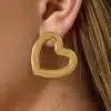 Du trägst einen großen, goldenen Open-Heart-Ohrring und die zarten Must-have Ohrstecker - modern, stilvoll und einzigartig.