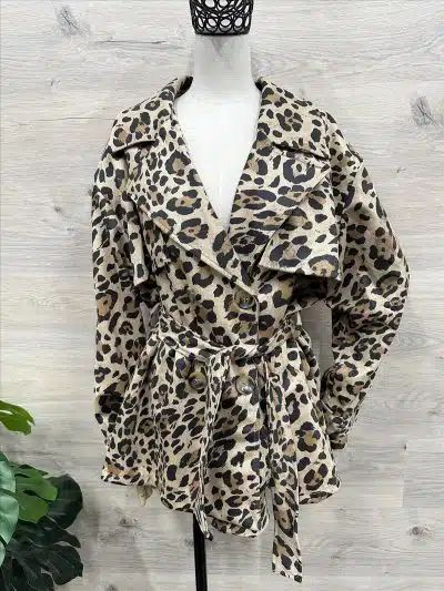 Entdecke die Street Safari Jacke - dein trendiges Leoparden-Trenchcoat-Statement vor stilvollem, hellem Holz-Backdrop.