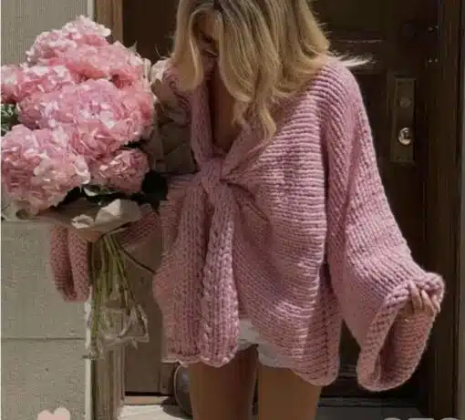 Du strahlst in deinem grob gestrickten Knoten-Pulli in zartem Rosa und setzt mit dem pinken Blumenstrauß ein echtes Statement.