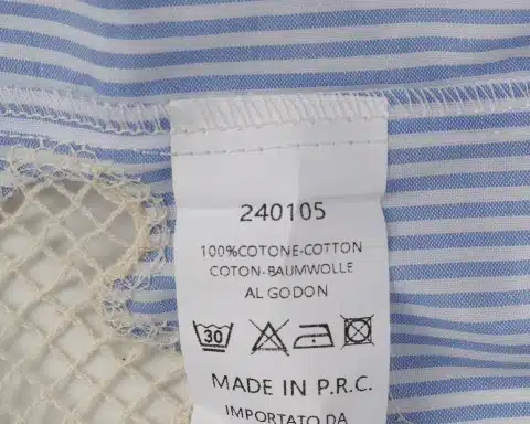 Entdecke das angesagte Label auf dem blau-weißen Stoff deiner Seaside Bluse - stylisch, informativ und perfekt für deinen Beach-Look.