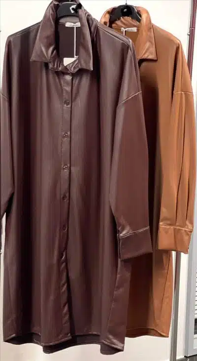 Entdecke deinen neuen Style: Zwei langärmelige Hemden aus hochwertigem, veganem Leder - eines in elegantem Dunkelbraun, das andere in trendigem Karamell-Ton. Die modernen Button-Down-Hemden hängen an schwarzen Kleiderbügeln und warten nur darauf, dein Outfit auf das nächste Level zu heben. Entscheide dich für deine Favoriten und setze ein Statement - zeitgemäß, bewusst und absolut angesagt!.