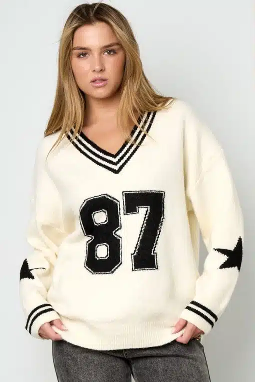 Entdecke deinen Style: Im cremefarbenen Varsity Star Pulli mit coolen Streifen, Nummer 87 und Stern-Designs setzt du Trends.