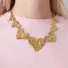 Trage ein pinkes Shirt und verleihe deinem Look mit einer goldenen Halskette voller gehämmerter Herzanhänger modernen Glam.