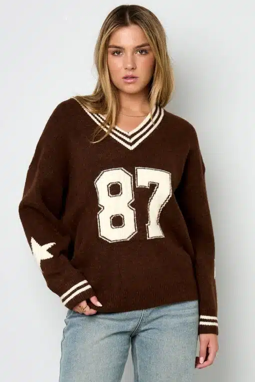 Zieh dir deinen coolen Braunpullover mit "87" und Sternen an den Ärmeln an - dazu lässige hellblaue Jeans, fertig!.