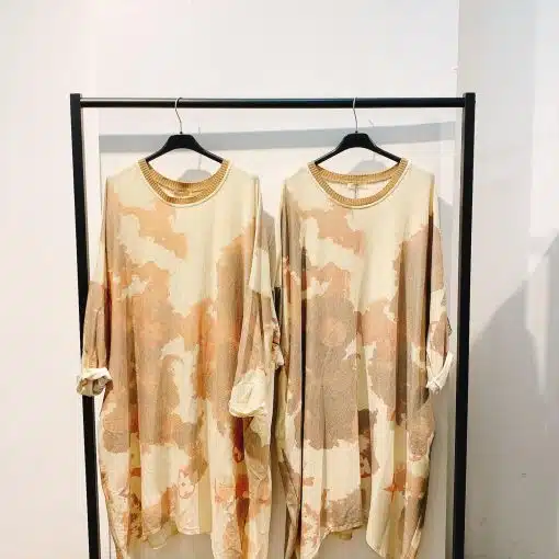 Entdecke dein neues It-Piece: Die Sahara Sunset Oversize-Kleider in Beige und Braun warten stylish am schwarzen Kleiderständer auf dich!.