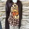 Entdecke deinen Style: Trage das Valentina Longhemd aus braunem Leder, Leo-Shirt und beiger Hose vor urbaner Steinwand!.
