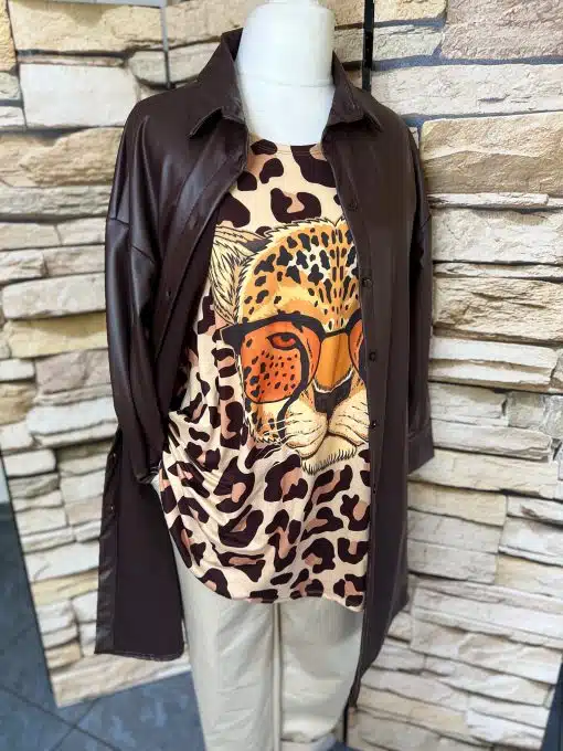 Entdecke deinen Style: Trage das Valentina Longhemd aus braunem Leder, Leo-Shirt und beiger Hose vor urbaner Steinwand!.