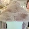 Entdecke deinen neuen Look: Hülle dich in dieses edle, hellbraune Kunstfell-Cape und strahle moderne Eleganz aus.