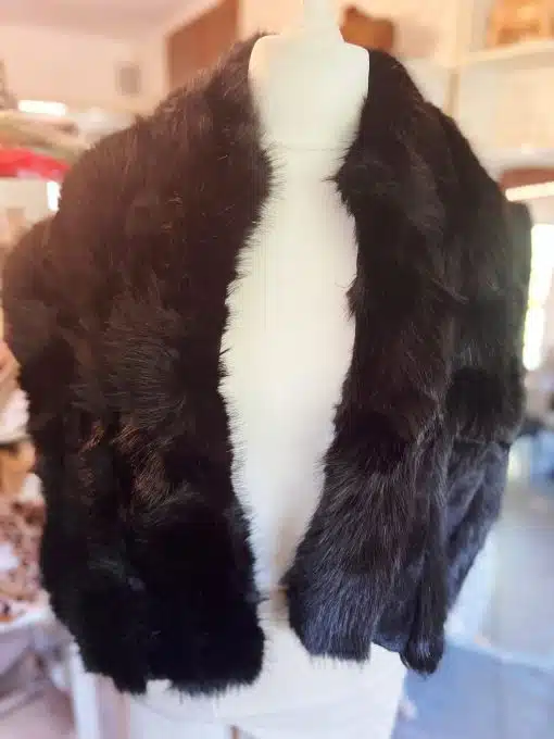 Entdecke deinen neuen Look: Ein schwarzer Kunstfell-Schal verleiht jedem Outfit an der weißen Schneiderpuppe modernen Chic.