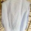 Erlebe die Seaside Bluse: Zeitloses Streifendesign in Hellblau und Weiß, perfekt präsentiert vor stilvoller Steinoptik - für deinen Look!.