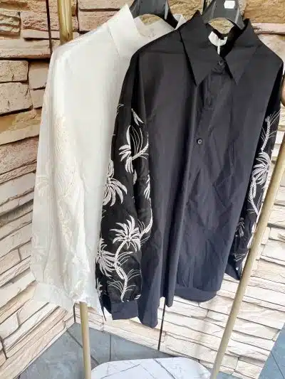 Erweitere deinen Look mit zwei angesagten "Tropical Elegance" Blusen-weiß und schwarz, beide mit weißen Blumenstickereien.