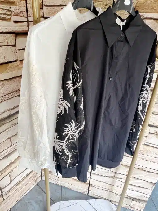 Erweitere deinen Look mit zwei angesagten "Tropical Elegance" Blusen-weiß und schwarz, beide mit weißen Blumenstickereien.