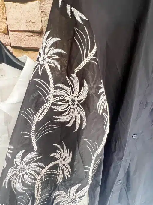 Entdecke deinen tropischen Look: Die "Tropical Elegance" Bluse mit schwarzen Palmen auf Weiß verleiht dir modernen Chic.