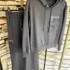 Erlebe ultimativen Komfort: Das Urban Comfort Set - grauer Hoodie und passender Rock mit Zipper-Taschen vor Stone-Wall-Design.