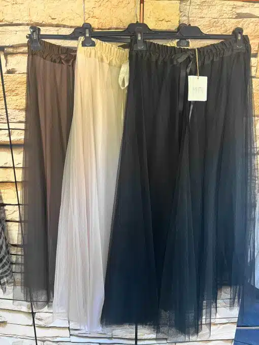 Entdecke deinen neuen Look: Die "Cloudlight"-Chiffonröcke in Braun, Creme und Schwarz warten stilvoll auf dich am Kleiderständer.